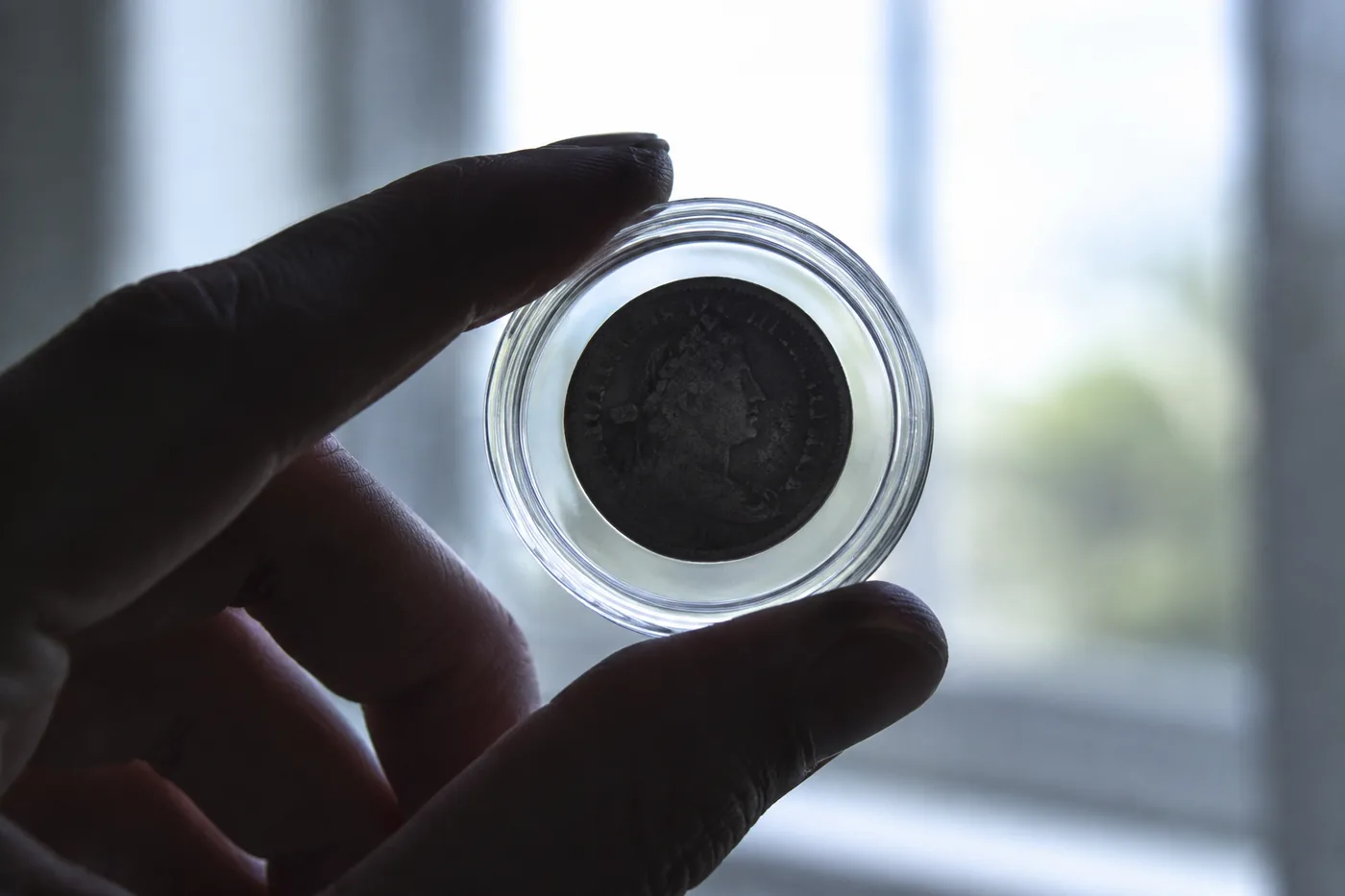 Small coin in capsule held against light